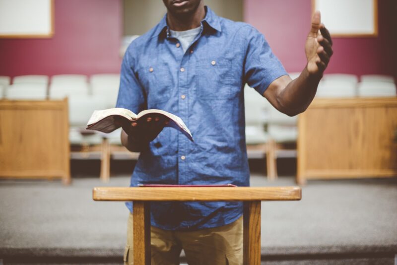 Closeup shot of a Black male reading the Bible in pulpit