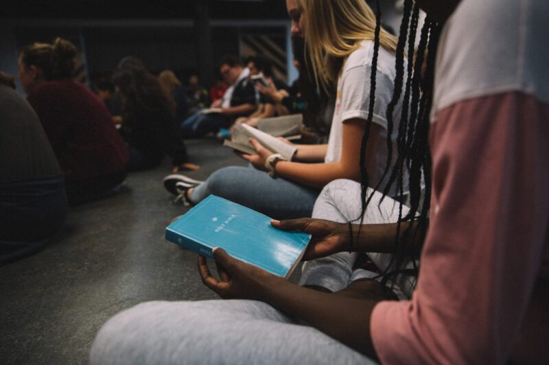Teenagers sitting in youth group holding Bibles