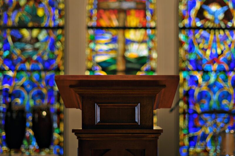 A wooden podium with stained glass in the background