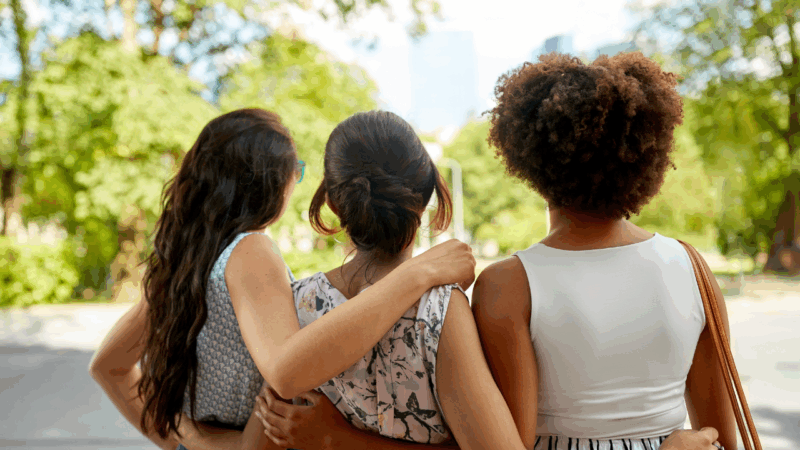 Three teen women with hugging with their backs to the camera