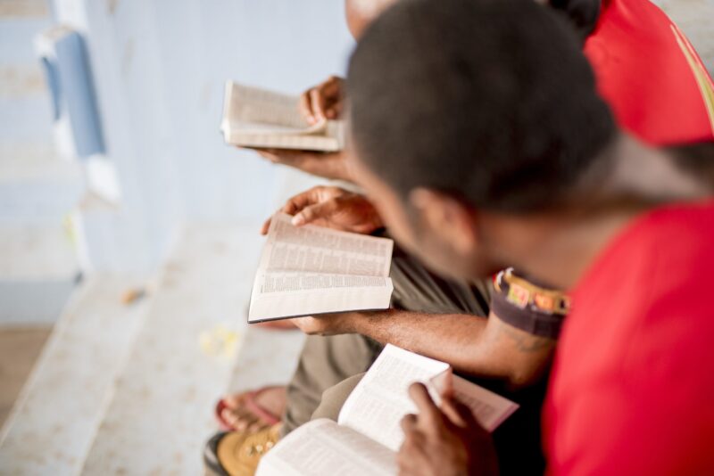 high-angle shot of people sitting near each other with Bibles open