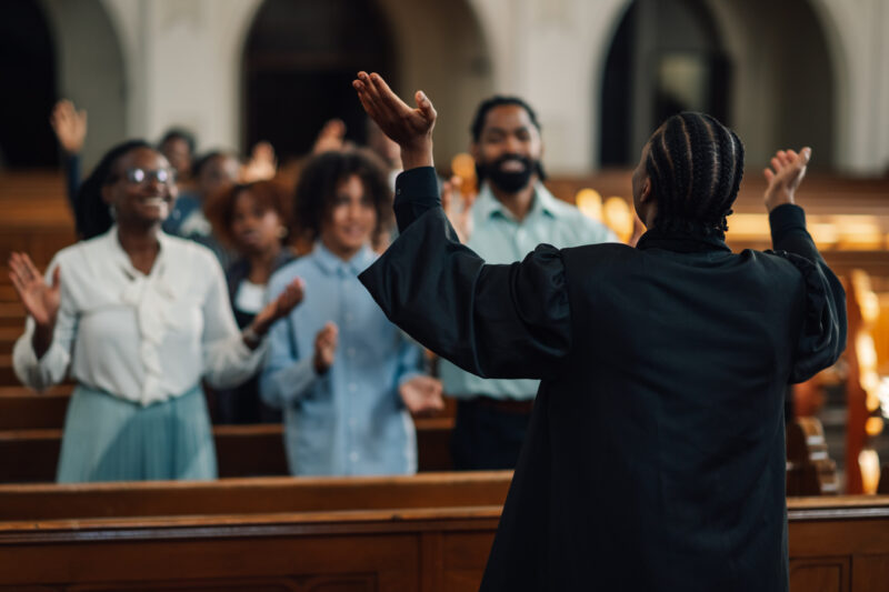 Preacher leading congregation in prayer inside church