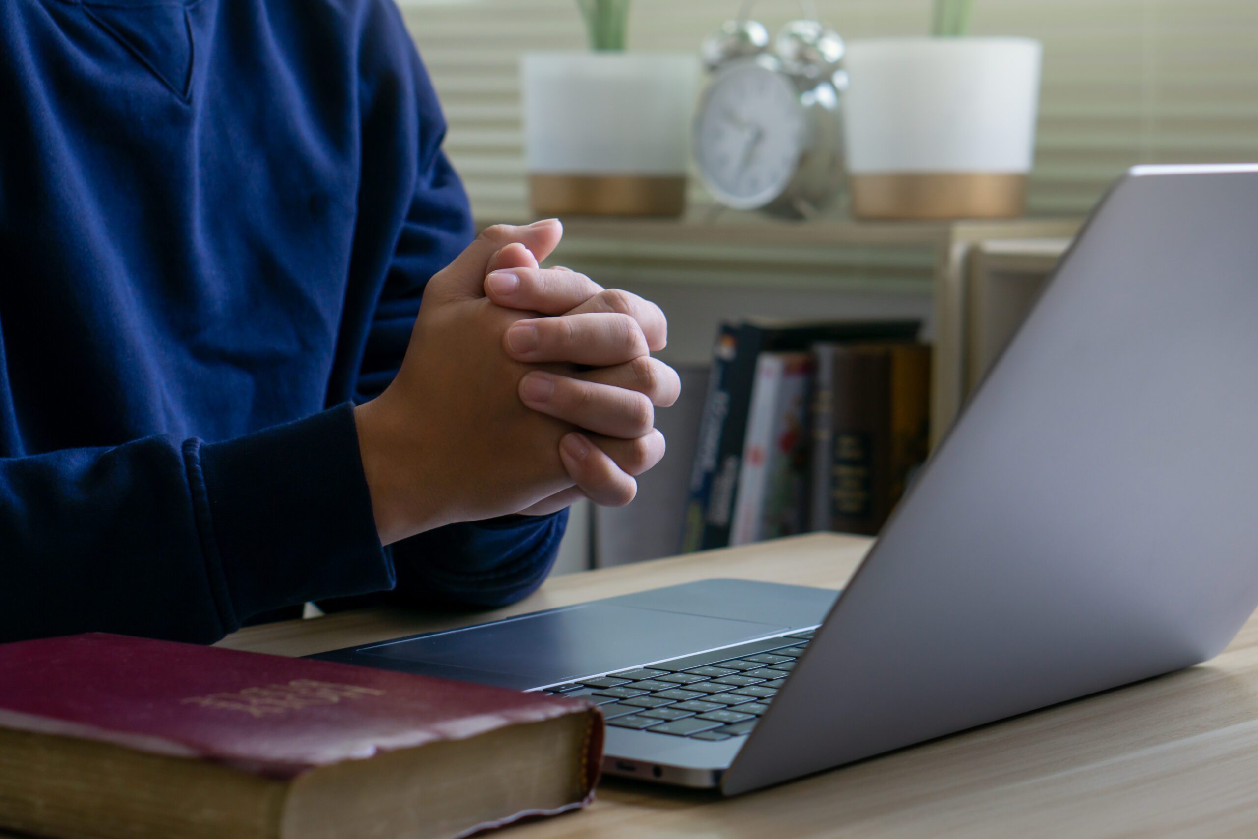Christian leader using a laptop computer with an open Bible on his desk during morning devotions