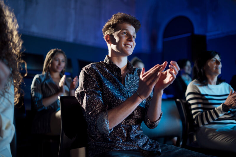 Group of people clapping while listening to presentation at conference