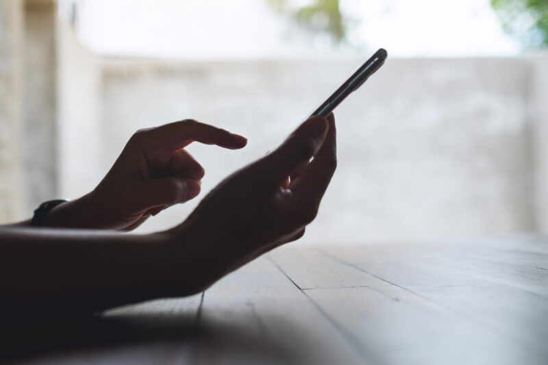 Closeup image of a hand holding and touching on mobile phone screen